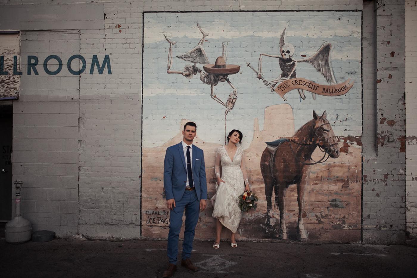 married couple standing in front of mural of horse