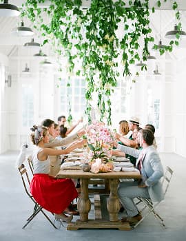 Long table set for a dinner party under greenery